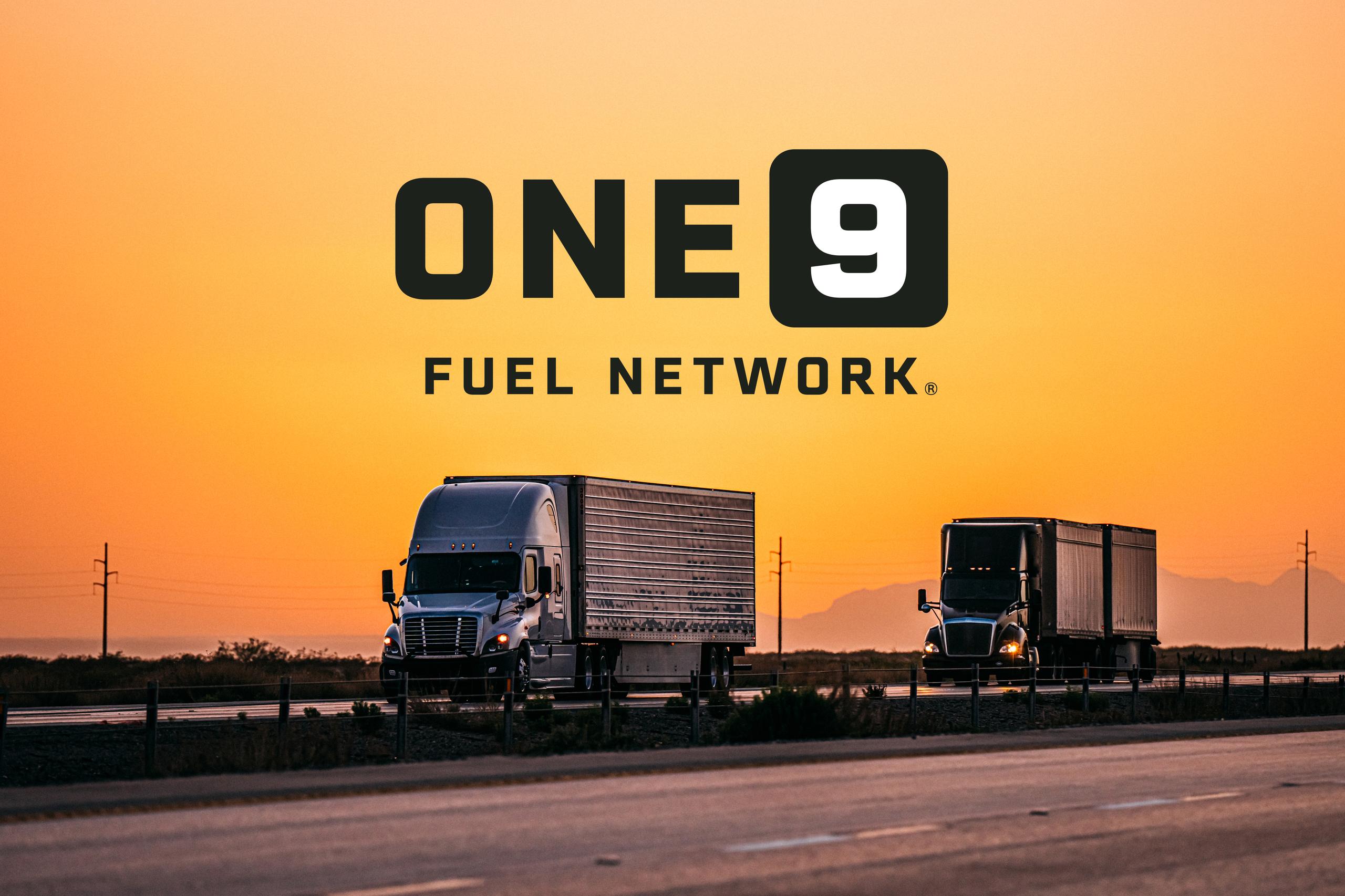 Two semi-trucks travel along a highway at sunset beneath the ONE9 Fuel Network logo against an orange sky.