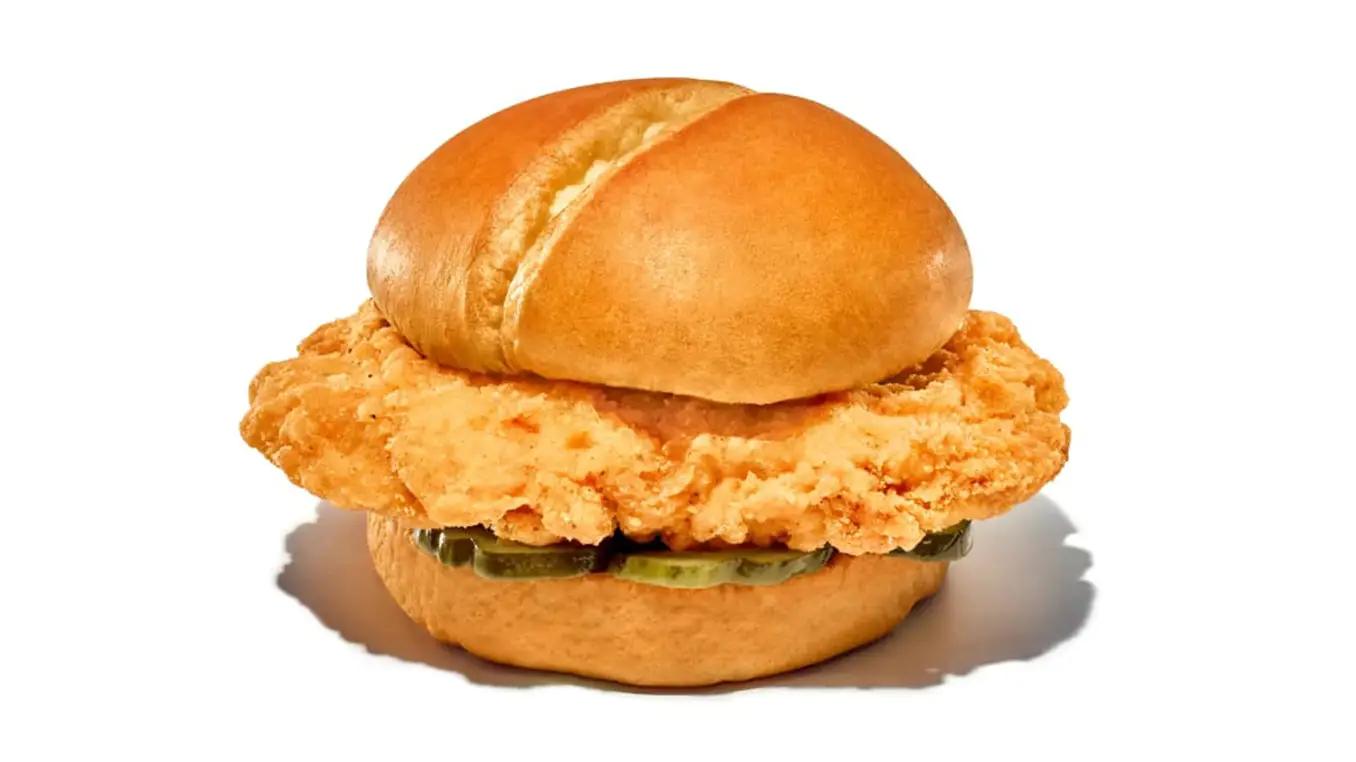 A crispy fried chicken sandwich with pickles on a white bun