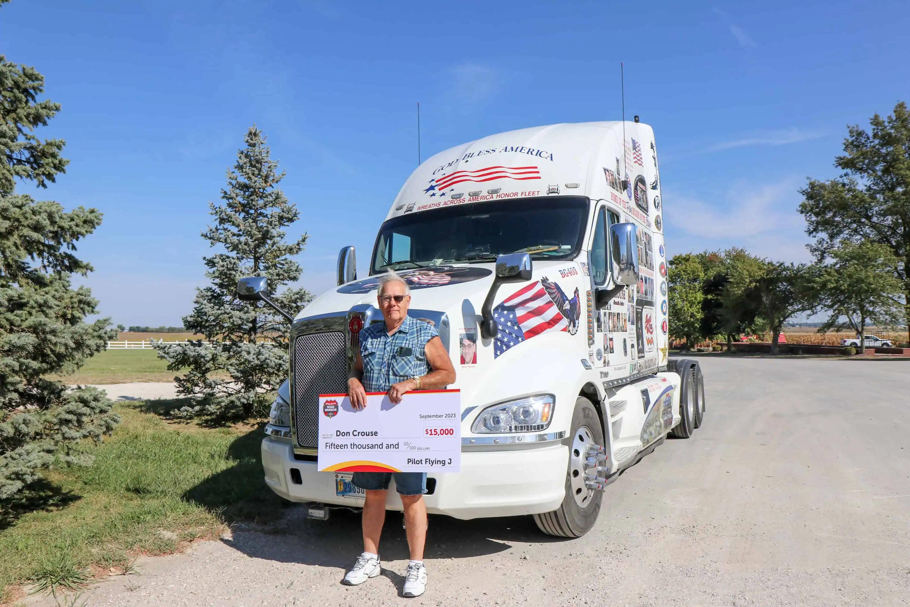 Man with an eye patch standing in front of a white semi truck covered in magnets