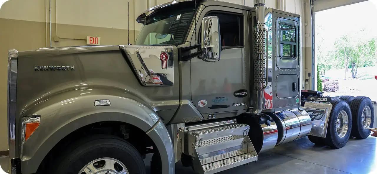 Gray Kenworth semi truck parked in a large garage