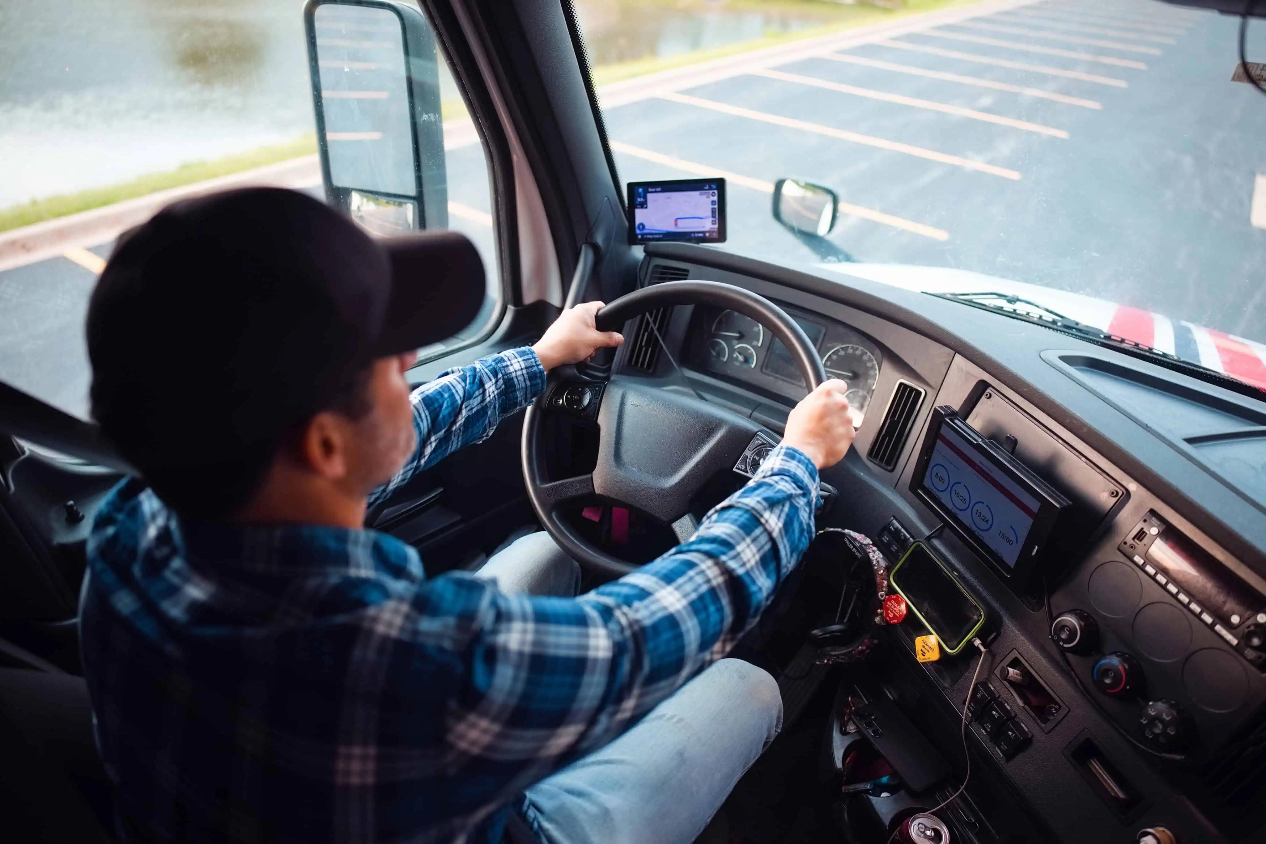Pro driver behind the wheel of a semi truck leaving a parking lot
