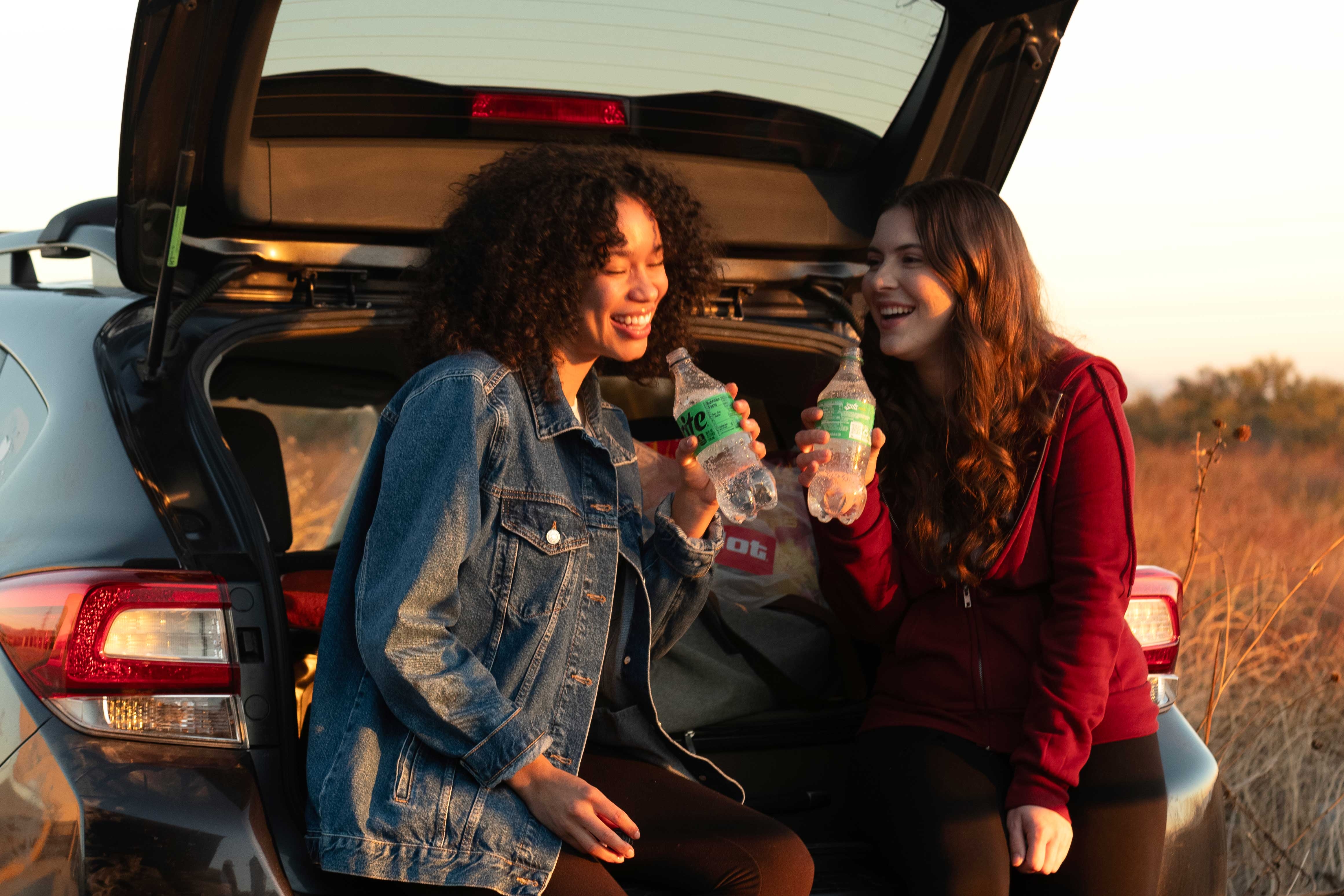 Two women on road trip hanging out in back of car admiring the view