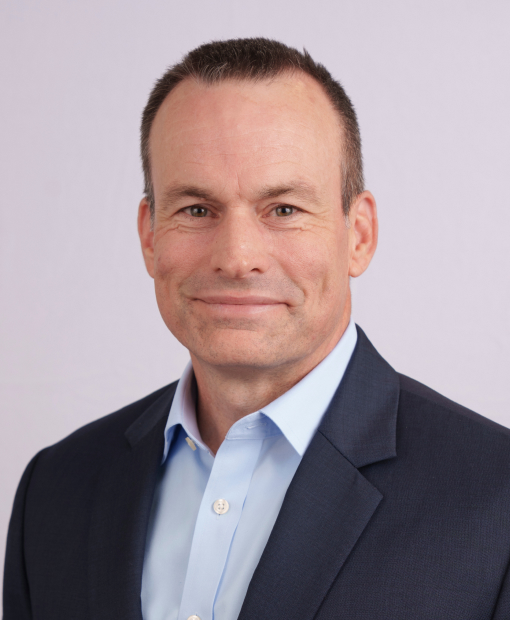 Professional headshot of Jeremy Osterstock wearing a navy jacket with a light blue button down shirt