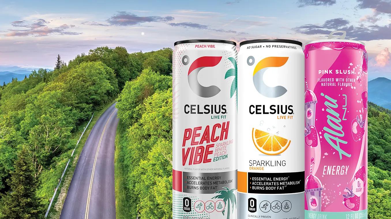 Two Celsius drink cans and one Alani Nu displayed on a scenic open road with green hills and blue sky.