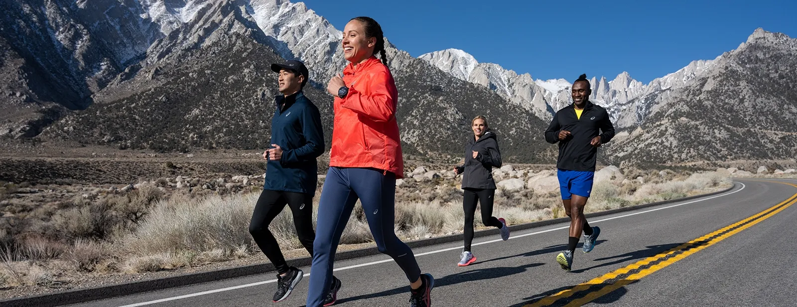 Four runners running outside near snow mountains