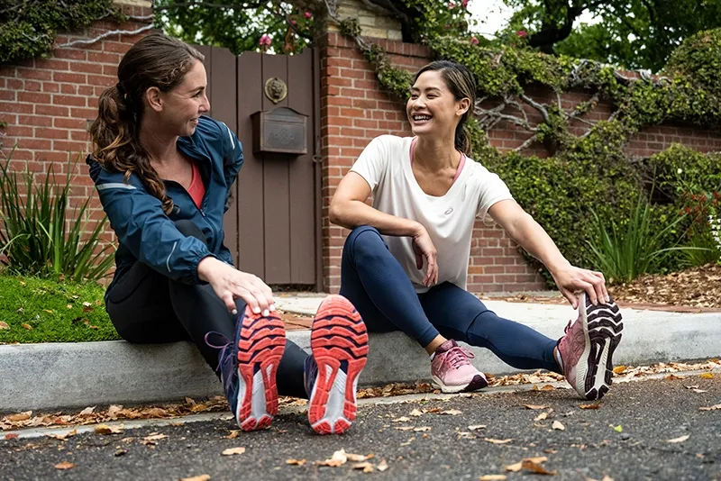 Two people stretching outside after a run
