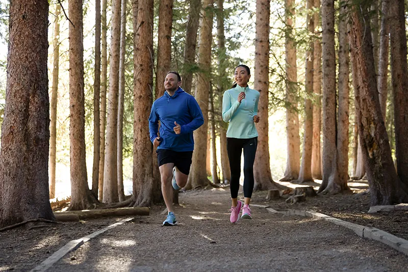 Two people running in woods