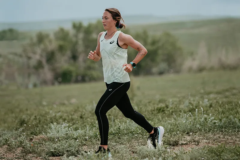 ASICS woman athlete running outside on a road trail
