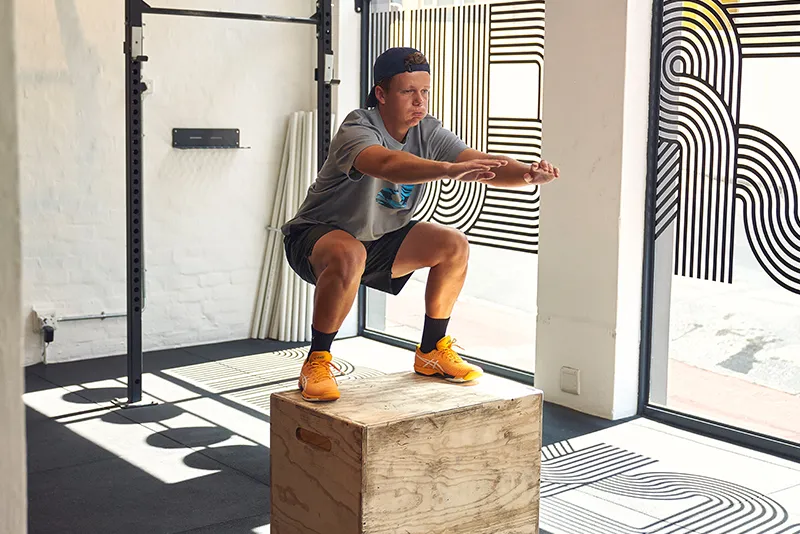 Man doing squat jump onto a box