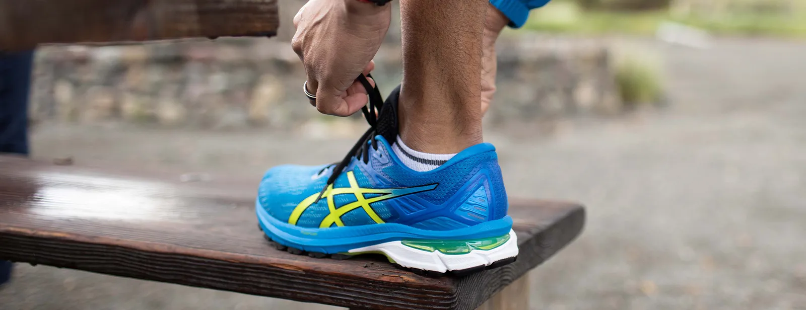 Man tying sneaker on bench