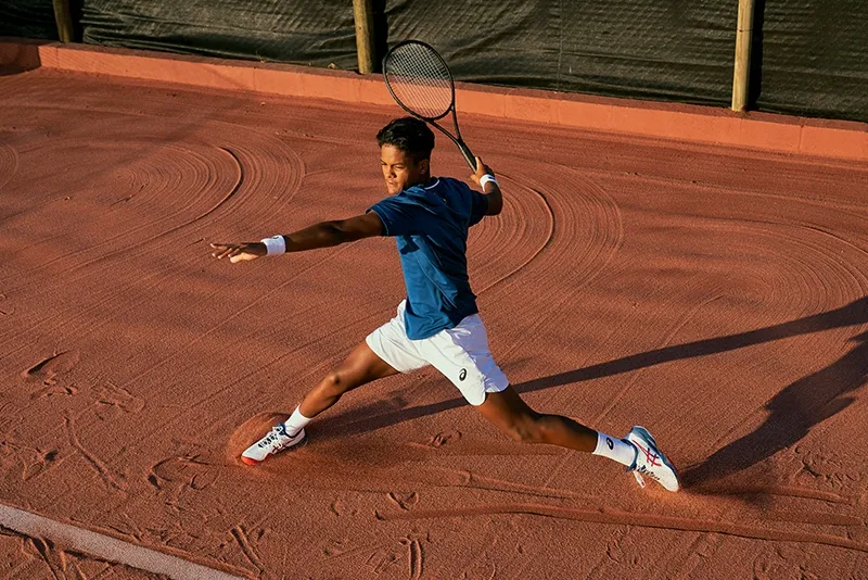 Man playing tennis of a clay court