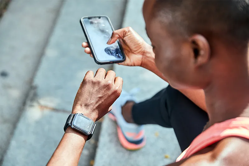 Runner looking at watch while holding a phone