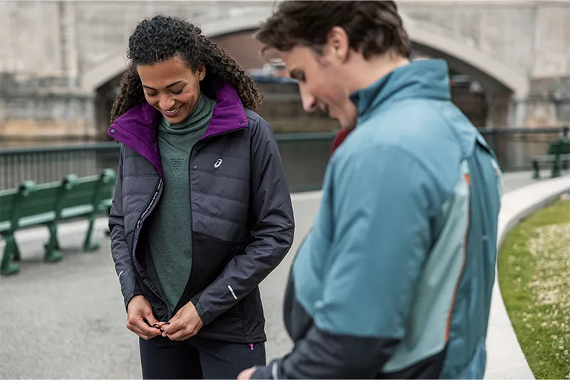 Two runners wearing multiple layers and zipping up