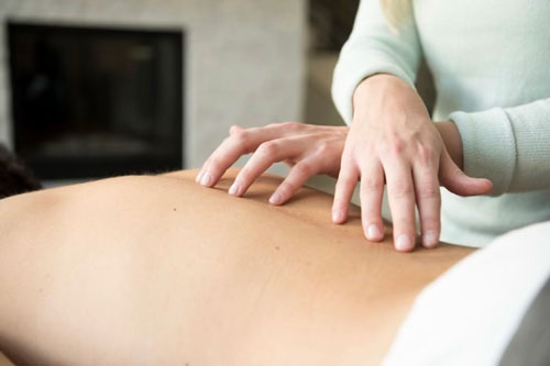 Hands applying the full AromaTouch Technique along the back
