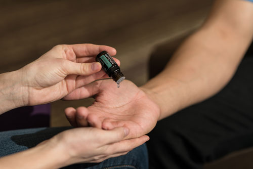 Essential oil being applied to an open palm during the AromaTouch Hand Technique