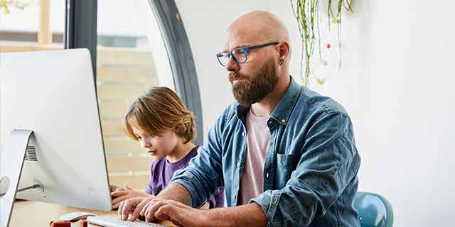 Father using computer to teach son about personal finance