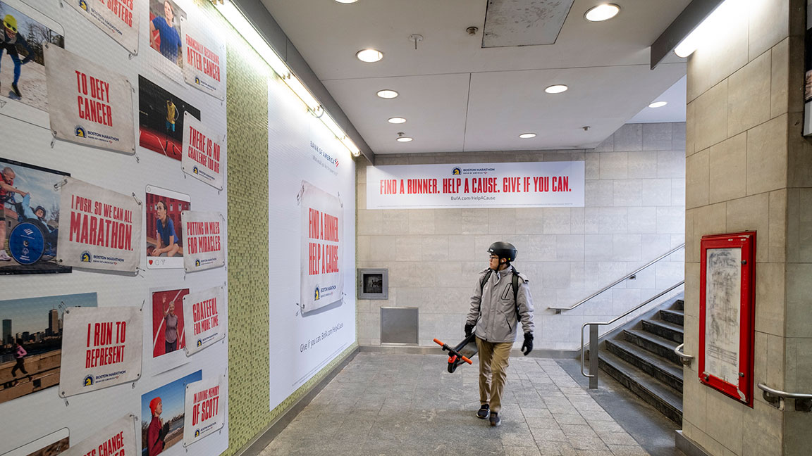 Bostonian walks through Station Domination ad campaign by Bank of America for the Boston Marathon