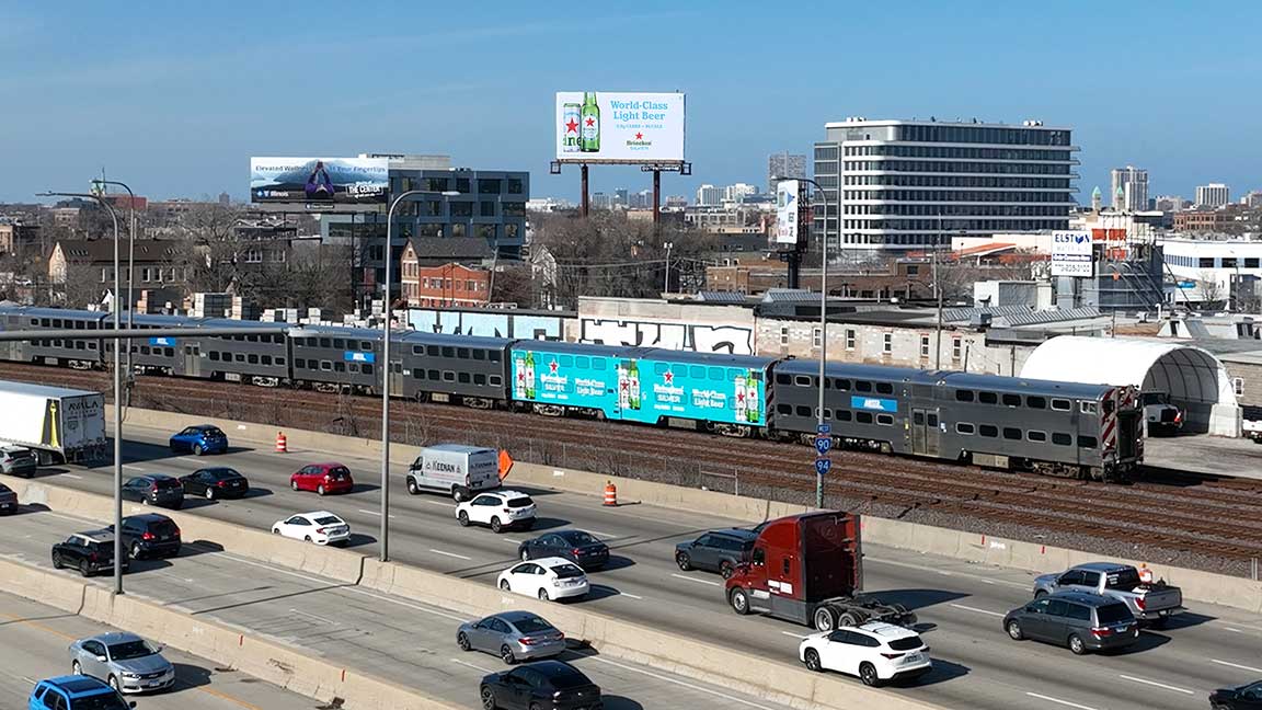 Metra commuter rail car with Heineken train wrap passes Heineken billboard along Kennedy Expressway in Chicago