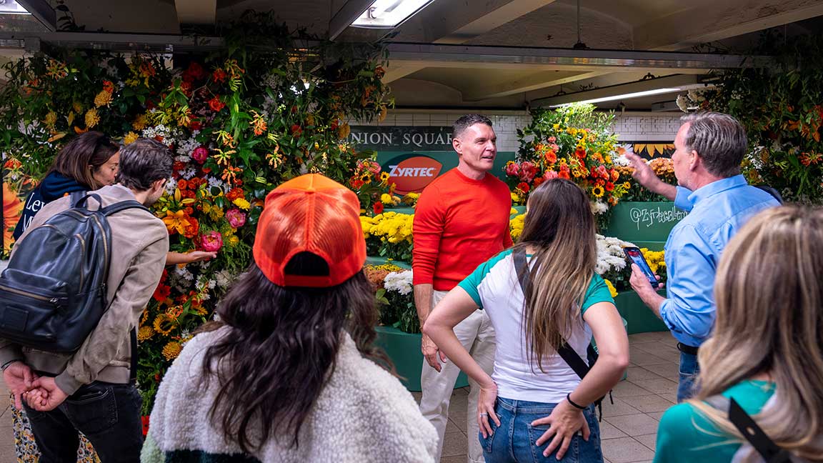 Lewis Miller speaks with commuters at Zyrtec Flower Flash installation at New York City subway station