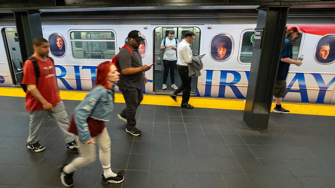 New York Subway riders walk past British Airways Shuttle wrap