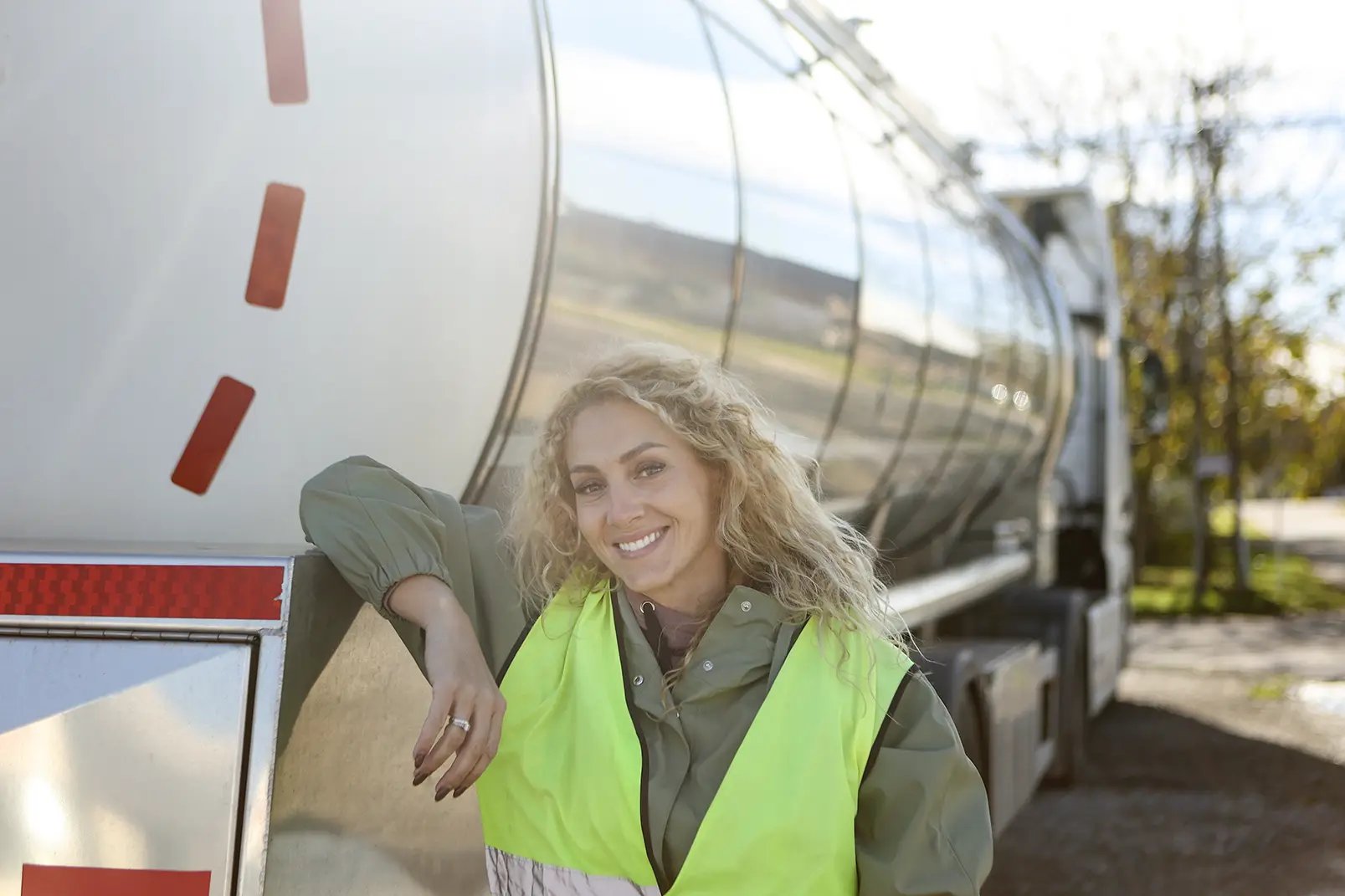 female driver leaning against fuel truck