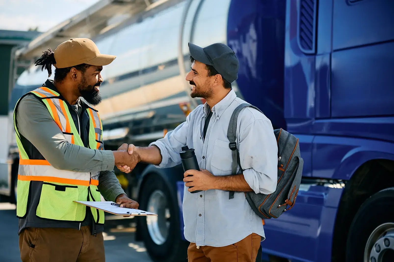 Two people stand in front of a truck shaking hands.
