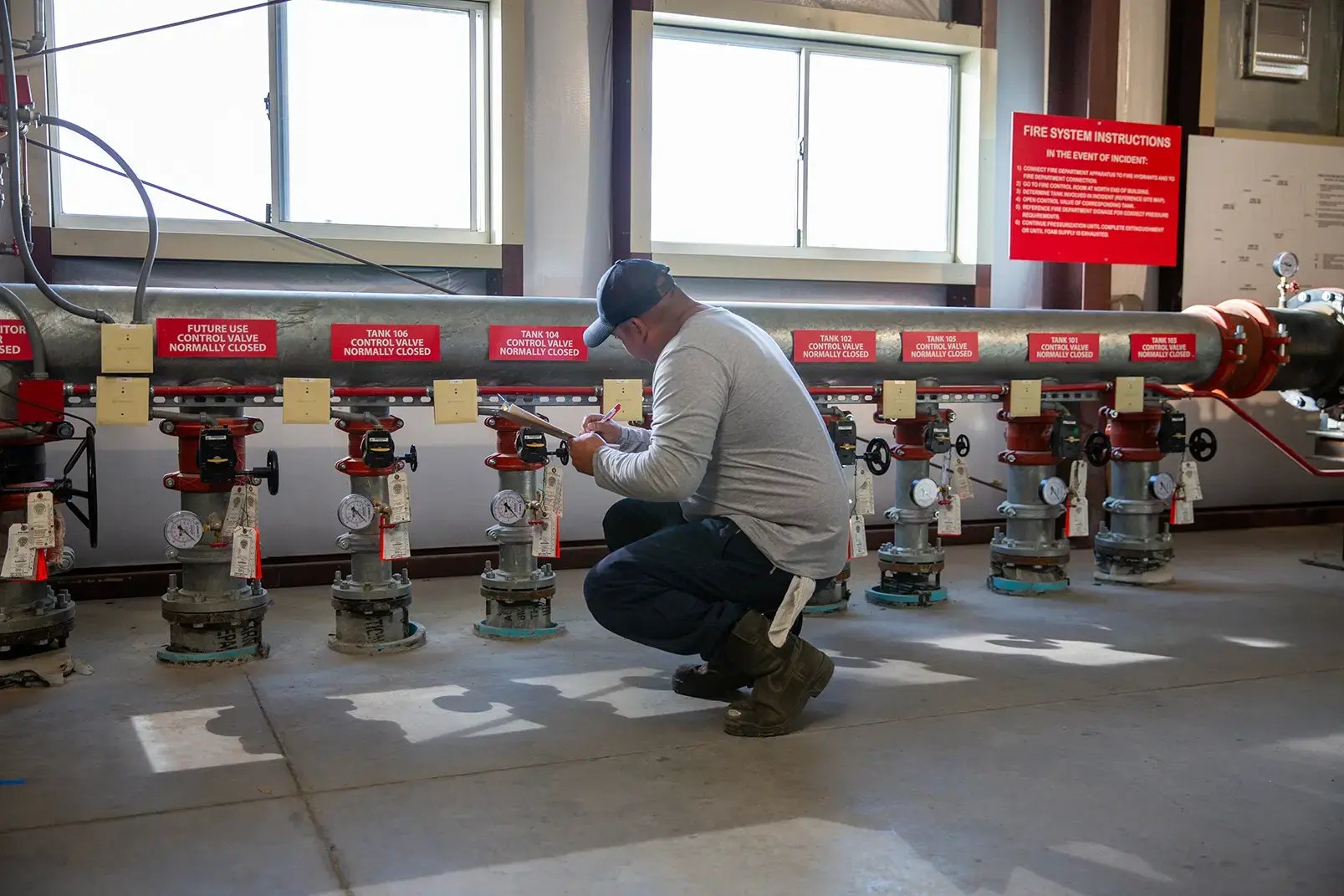 A person kneels in front of a fire control system.