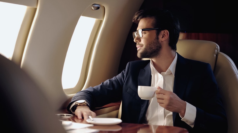 man holding espresso looking out airplane window