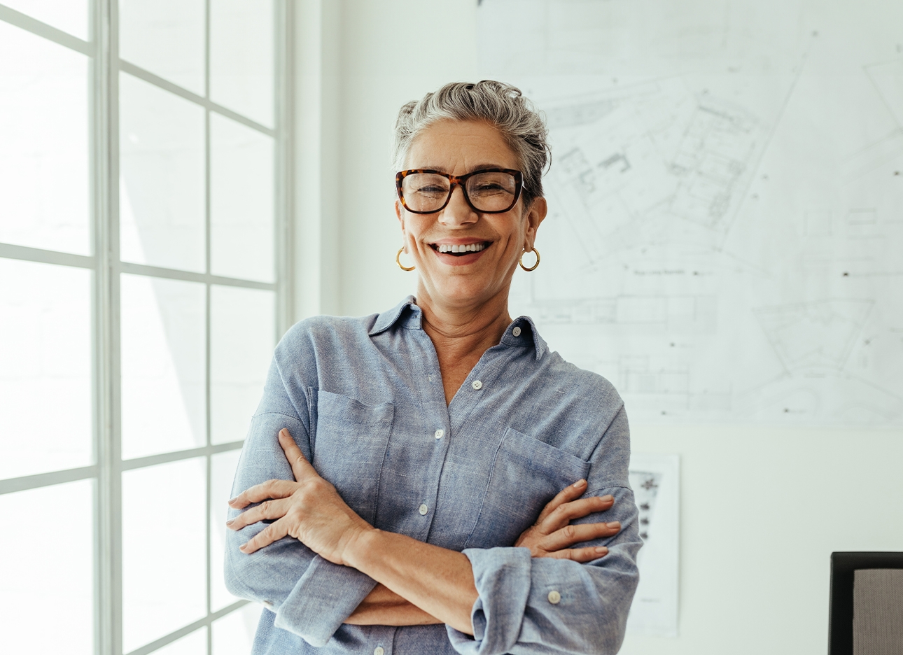 Woman standing at window with arms crossed