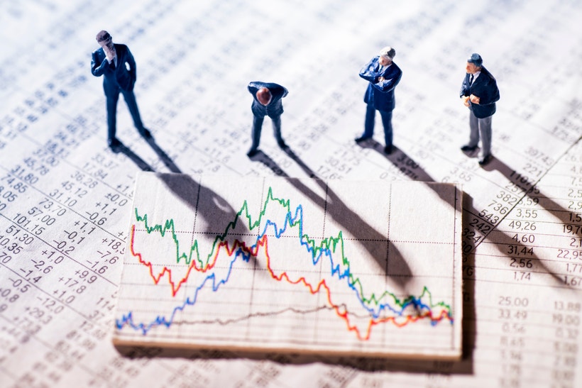 figurines on a stack of papers displaying line graphs