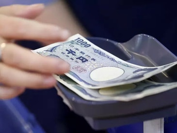 hand picking up a stack of japanese yen banknotes