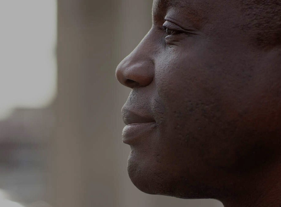 Close-up profile of a man looking off into the distance with a calm and content expression. The soft lighting highlights the contours of his face, and the blurred background adds depth to the image.