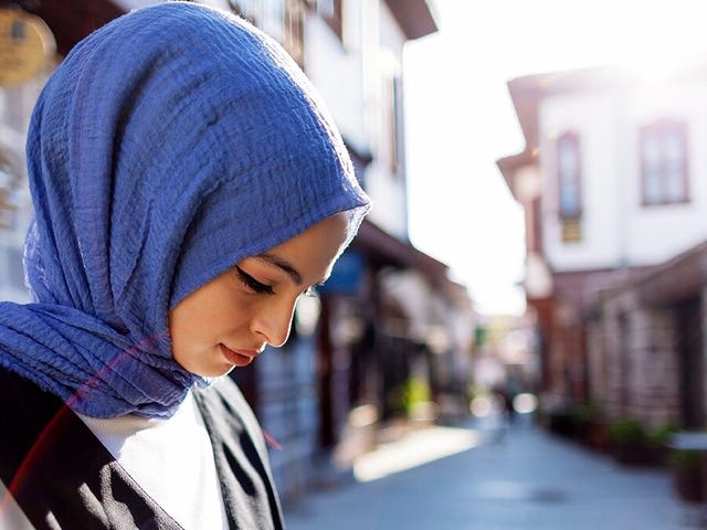 Woman standing on the street with her phone in her hand and studying a language online with a self-study course at Berlitz Algeria