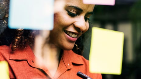 Woman writing on sticky notes during a IELTS preparation course with Berlitz Algeria