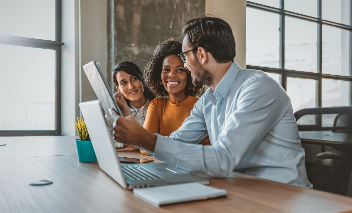 A man and two women in front of a laptop discussing job positions at Berlitz Algeria