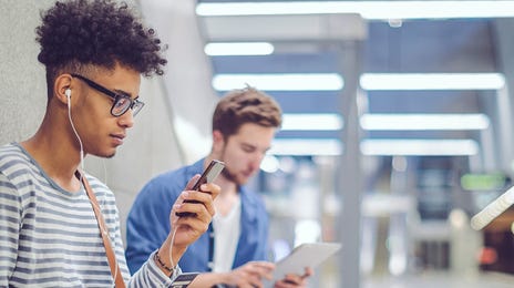 Man with headphones learning Arabic online from his phone while waiting for the metro