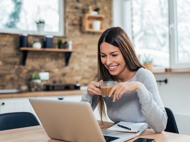 Woman in front of a computer holding a cup of coffee and taking a self study language course with Berlitz Algeria