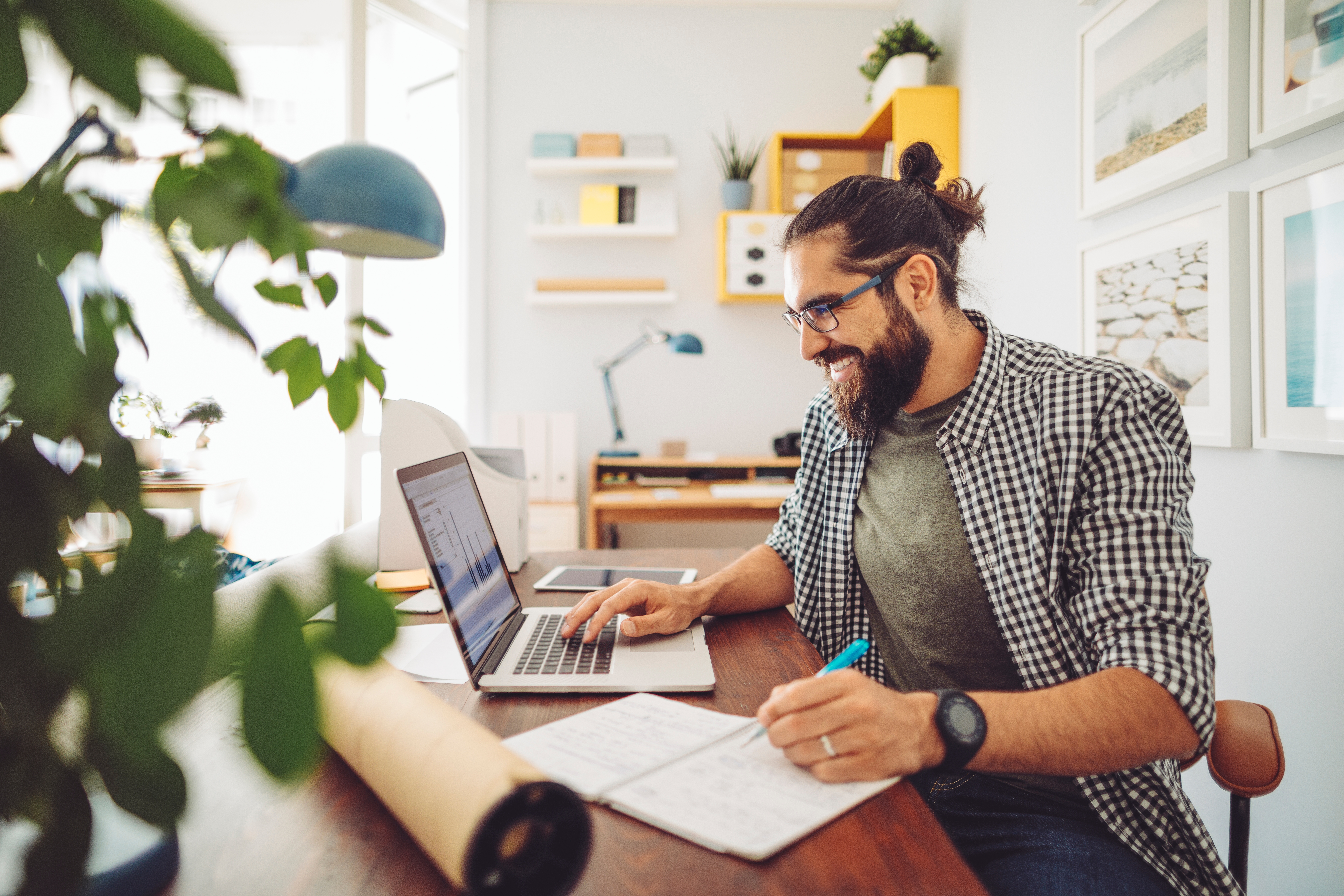 Man sitting at his desk in front a computer, taking an online language class with Berlitz Algeria and making notes