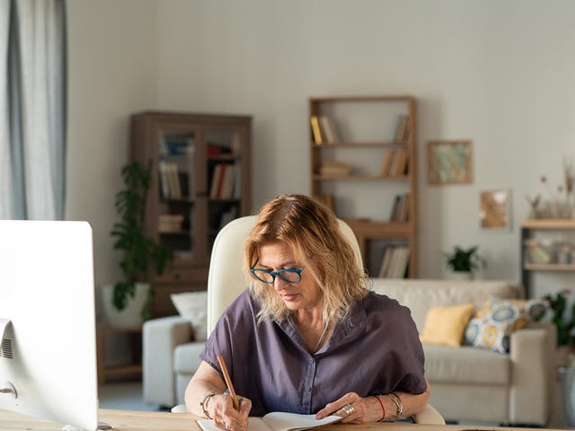 Woman learning a language with Berlitz's self-paced courses on her laptop and making notes in a notebook