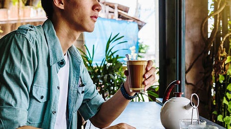 Man holding a glass of coffee after his Japanese class with Berlitz Algeria