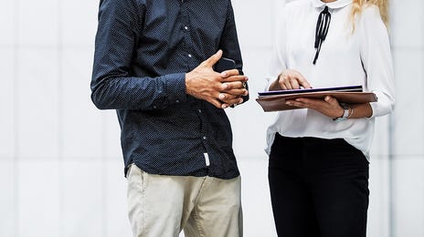 Man and woman in front of a building talking about the business services offered by Berlitz Algeria