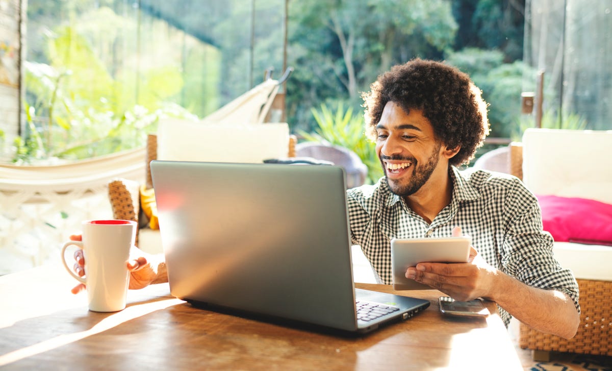Man in front of a laptop holding a notepad and learning a new language with Berlitz Connect