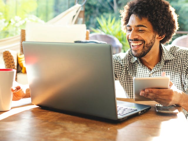 Man in front of a laptop holding a notepad and learning a new language with Berlitz Connect