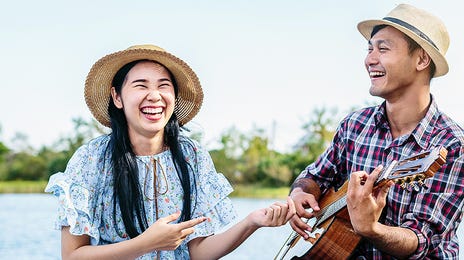 Man playing the guitar to his girlfriend and singing in Japanese