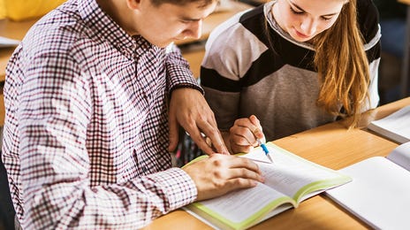 Students looking through their notes together during a group language class for kids and teens with Berlitz Algeria