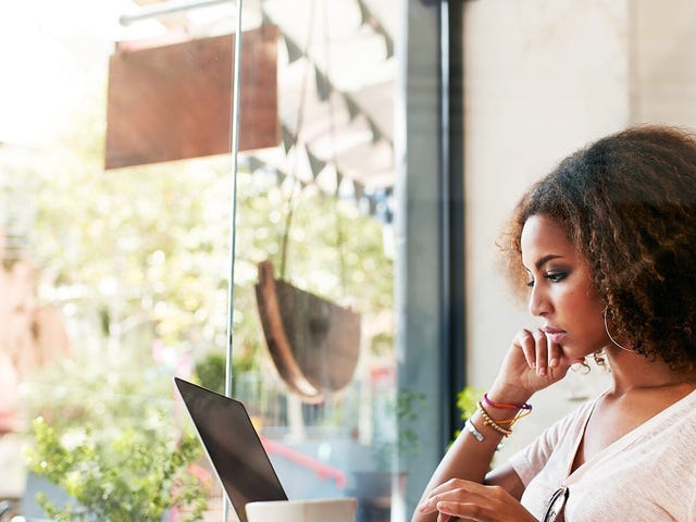 Woman in a coffee shop attending an online intensive language class with Berlitz Algeria from her laptop