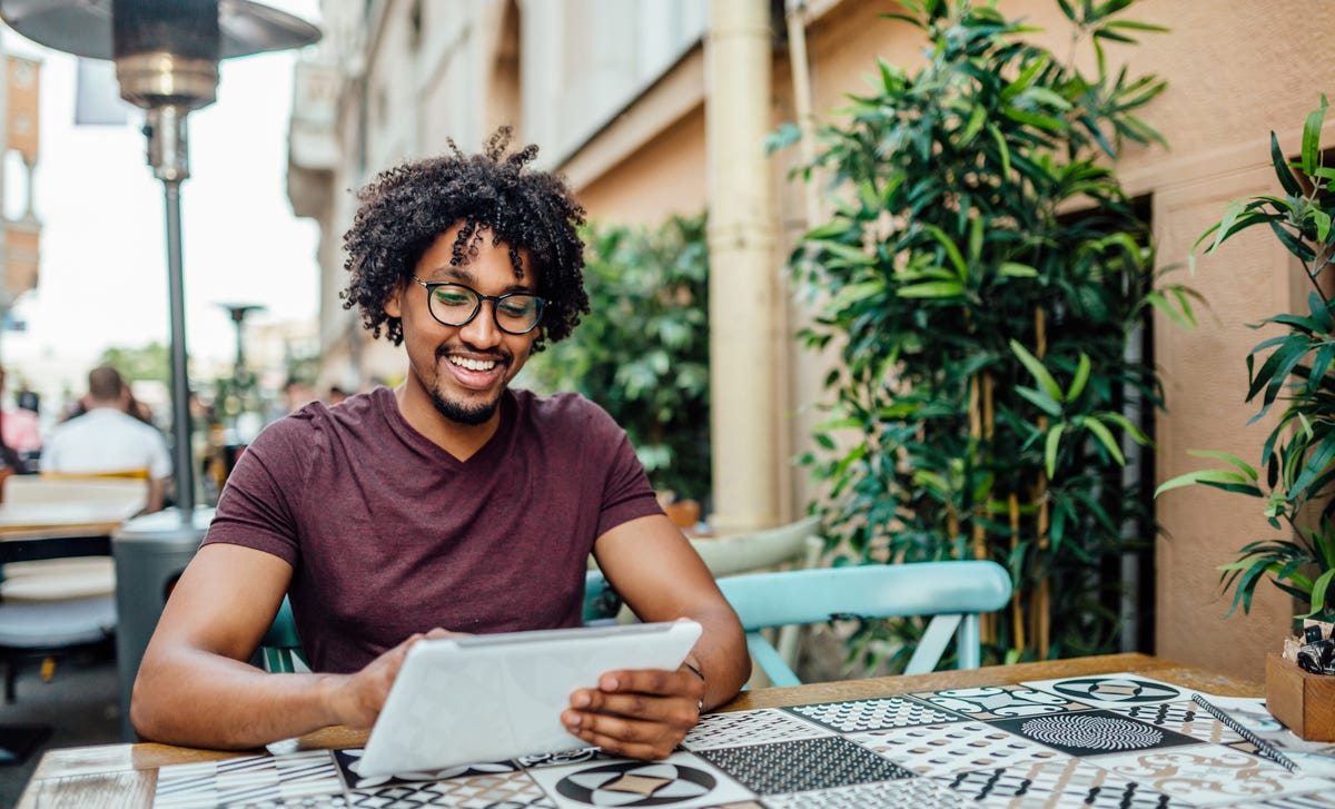 Man sitting outside at a table and learning French online on his tablet with Berlitz Algeria