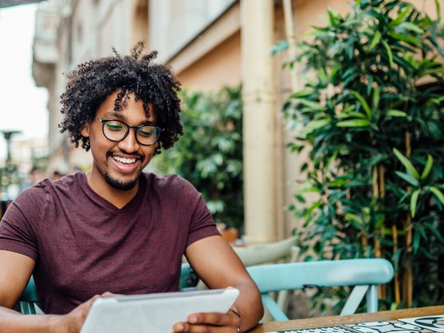 Man sitting outside at a table and learning French online on his tablet with Berlitz Algeria