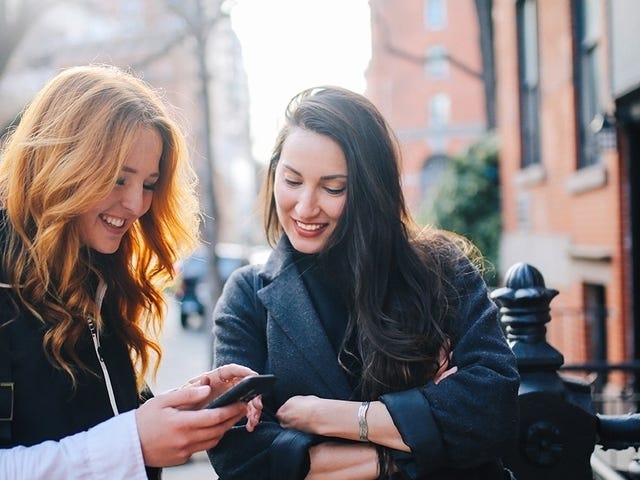 Women showing language courses to each other on their phones after a private language class