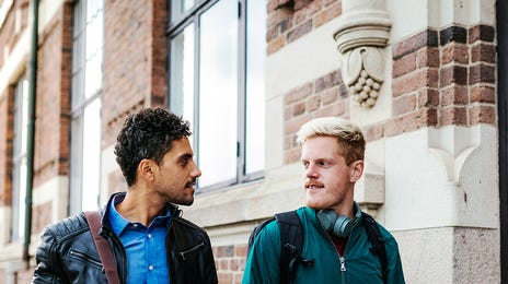 Two men walking together and chatting after their German class with Berlitz Algeria